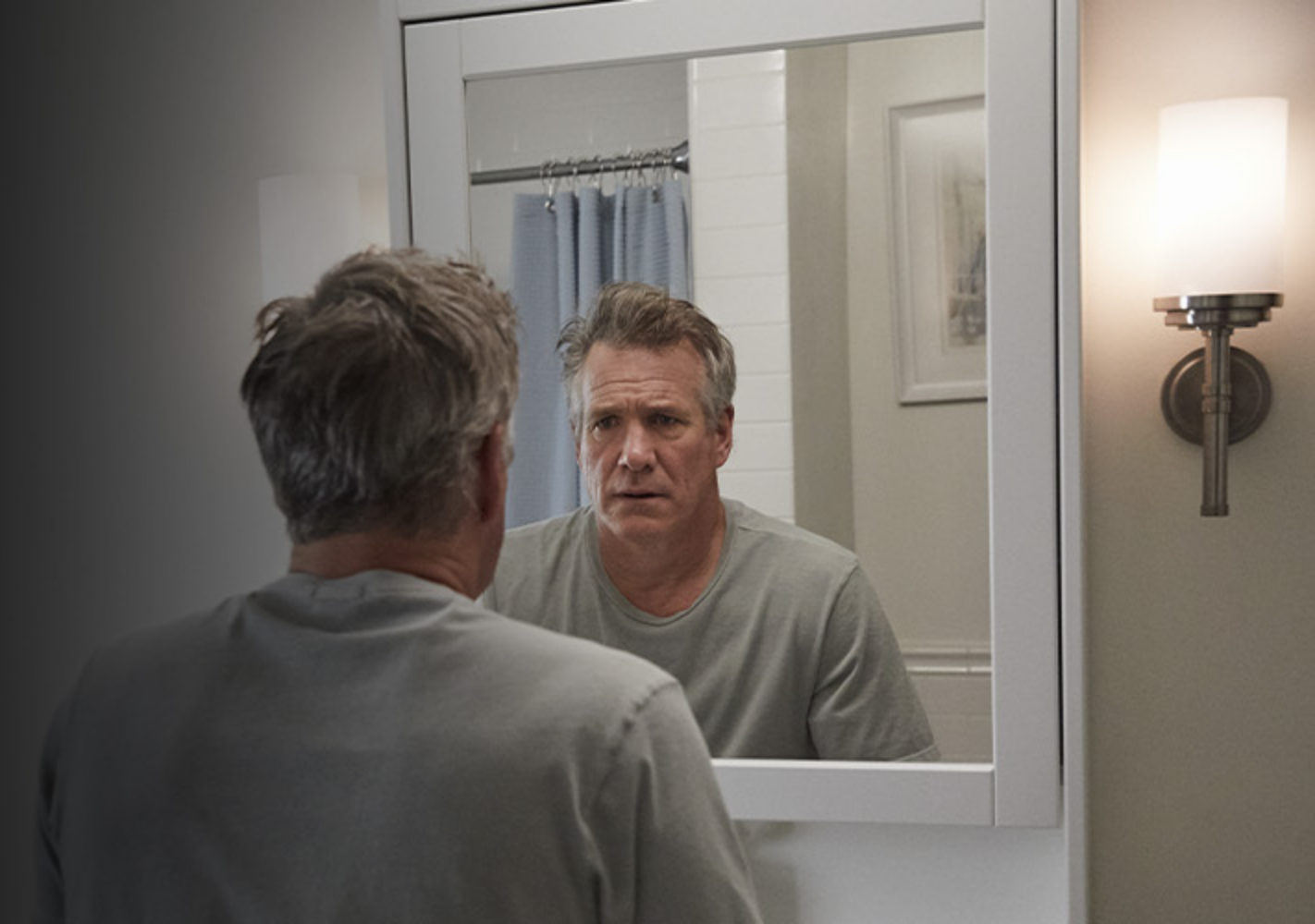 Image of a man looking at his reflection in the mirror.